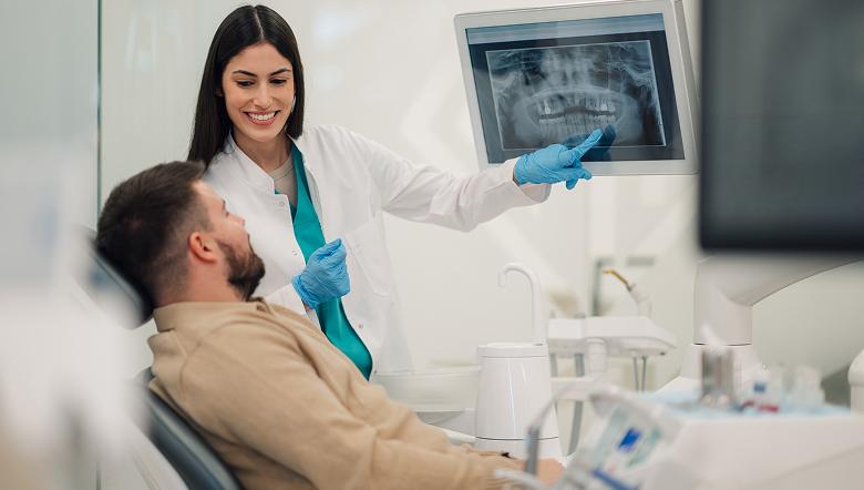 Dentist showing a patient their dental X-ray on a monitor during a consultation.
