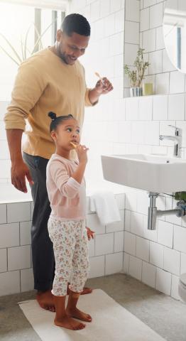 a dad and his daughter brush their teeth together