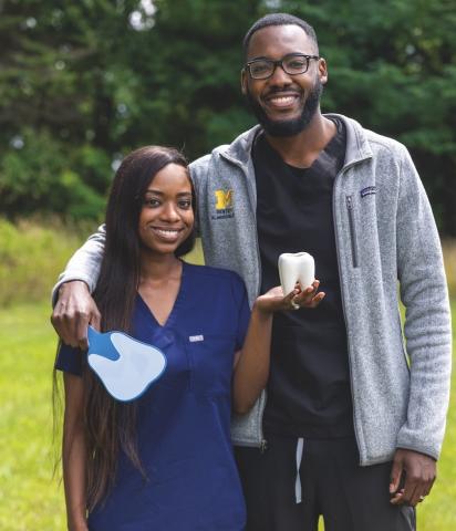 A male and female dentist couple stand smiling together