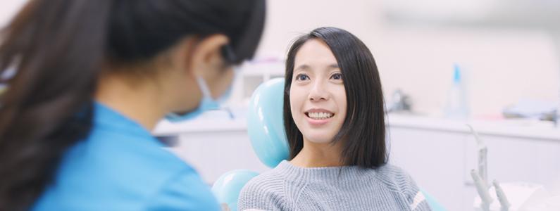 A woman smiles at a dental worker while sitting in a dentist's chair