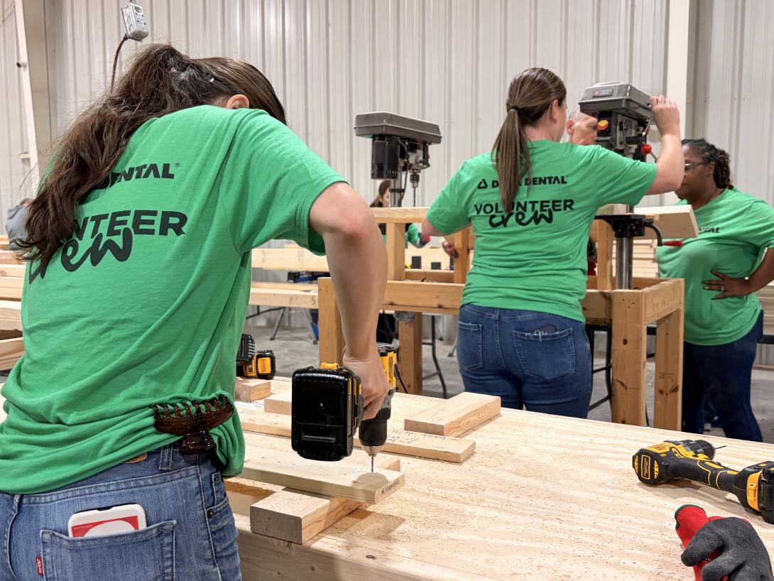 Delta Dental volunteers hard at work while wearing their green "Delta Dental volunteer crew" shirts.
