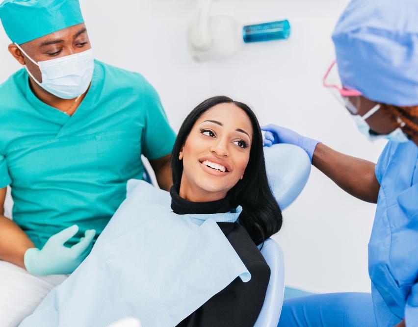 Woman in dentist chair with two dentists beside her
